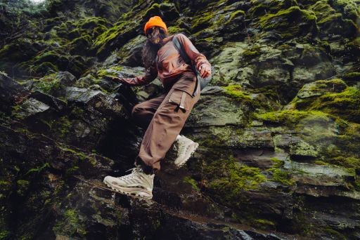 Woman climbing mossy rocks wearing Merrell Moab Speed 2 hiking shoes